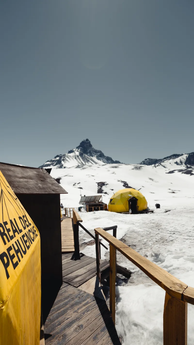 Domos geodésicos amarillos en la nieve con la cordillera de fondo
